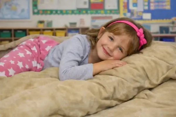 Ball_Blanket_Girl_laying_on-top-School-Setting_1536_1024 Child using sensory ball blanket in classroom setting