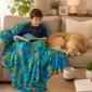 Child reading on a couch under an ocean fish weighted blanket.