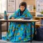 Child using an ocean fish weighted blanket while writing at a classroom desk.