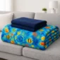 Folded ocean fish weighted blanket with navy blanket on a gray sofa.