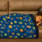 Child resting on a couch under a blue sea life weighted blanket.