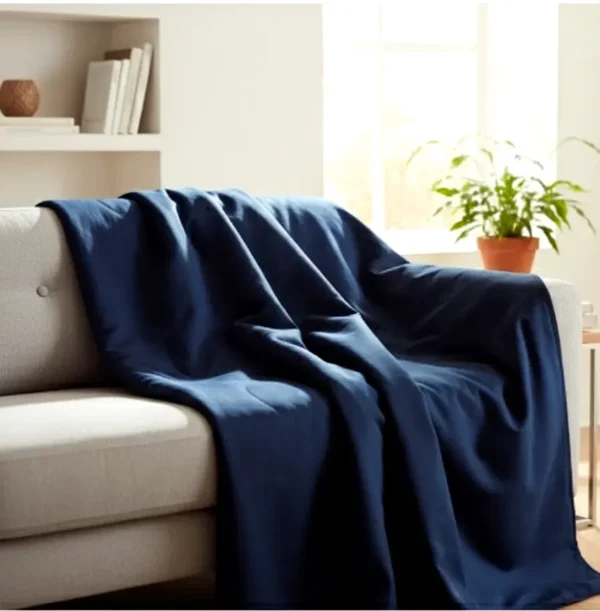 Navy Weighted Blanket on Sofa Navy weighted blanket draped over a sofa in a bright calming living room.