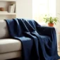Navy weighted blanket draped over a sofa in a bright calming living room.
