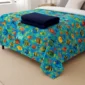 Ocean fish weighted blanket displayed on a bed with a folded navy blanket.