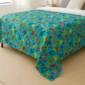 Colorful ocean fish weighted blanket displayed on a bed in a bright bedroom.